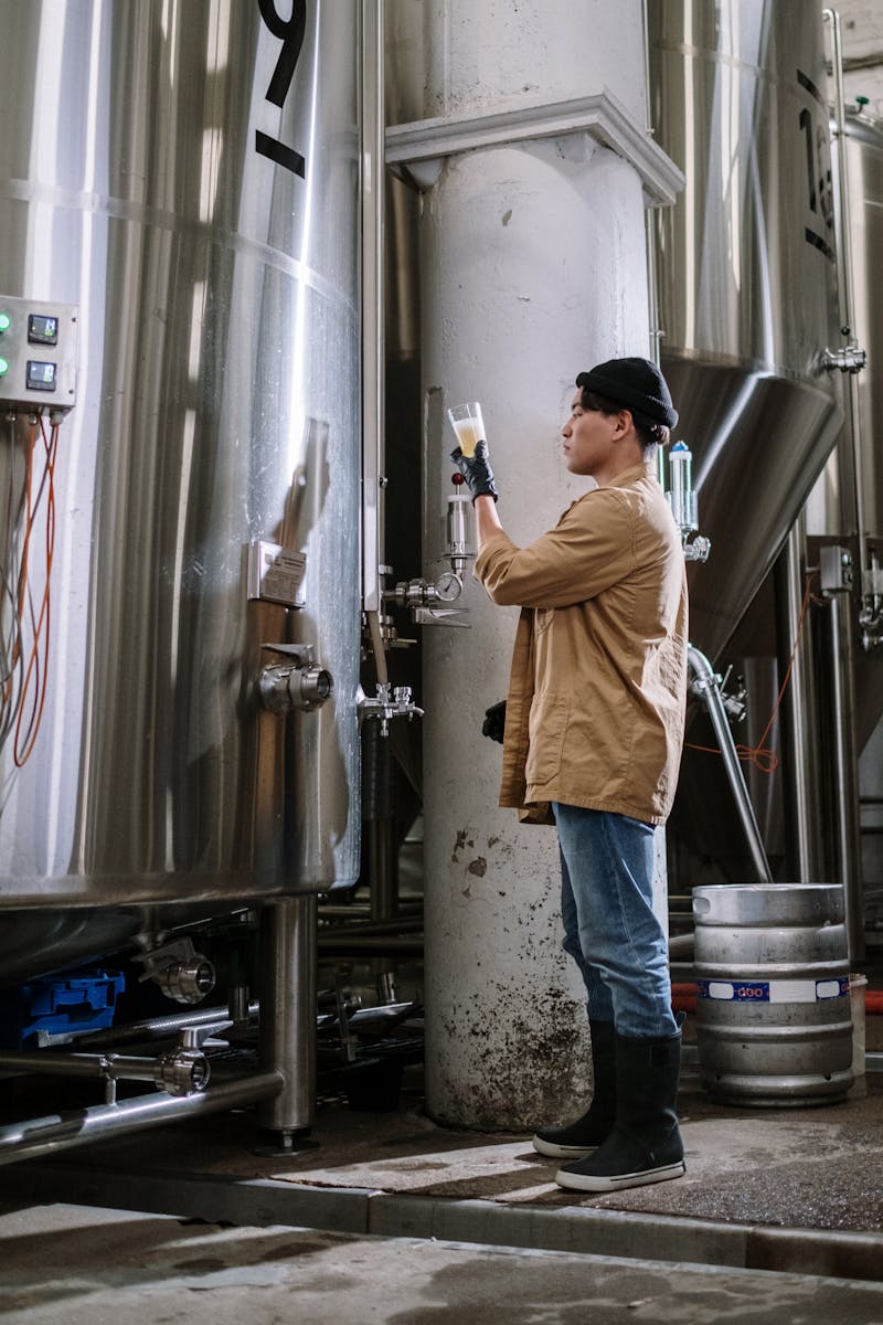 Brewmaster examining beer fermenter in a modern brewery - UK craft beer production