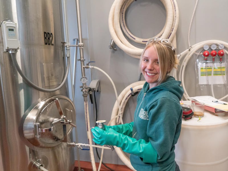 Brewery worker inspecting stainless steel equipment for quality control